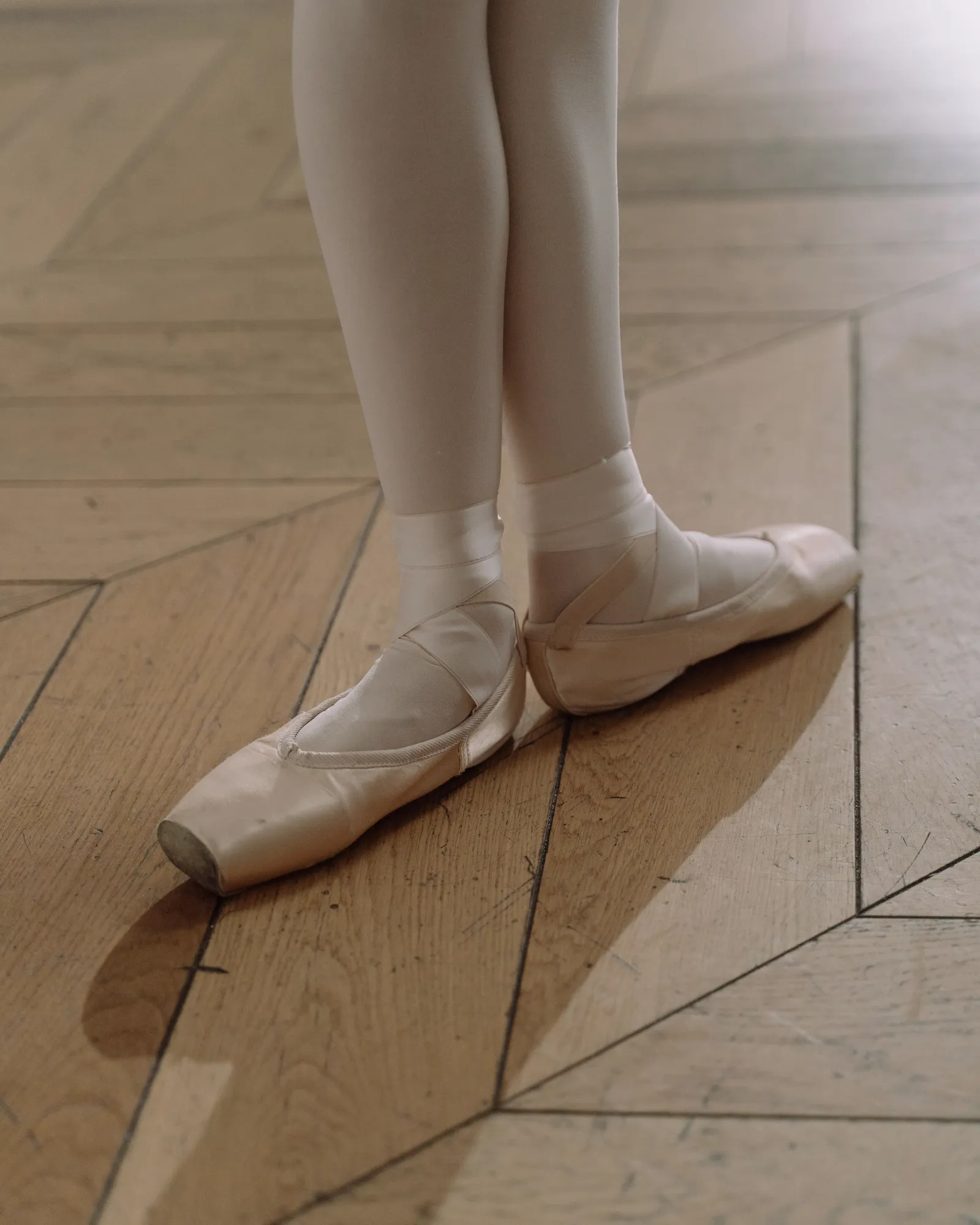 Detalle de zapatillas de punta sobre el parquet de un estudio.