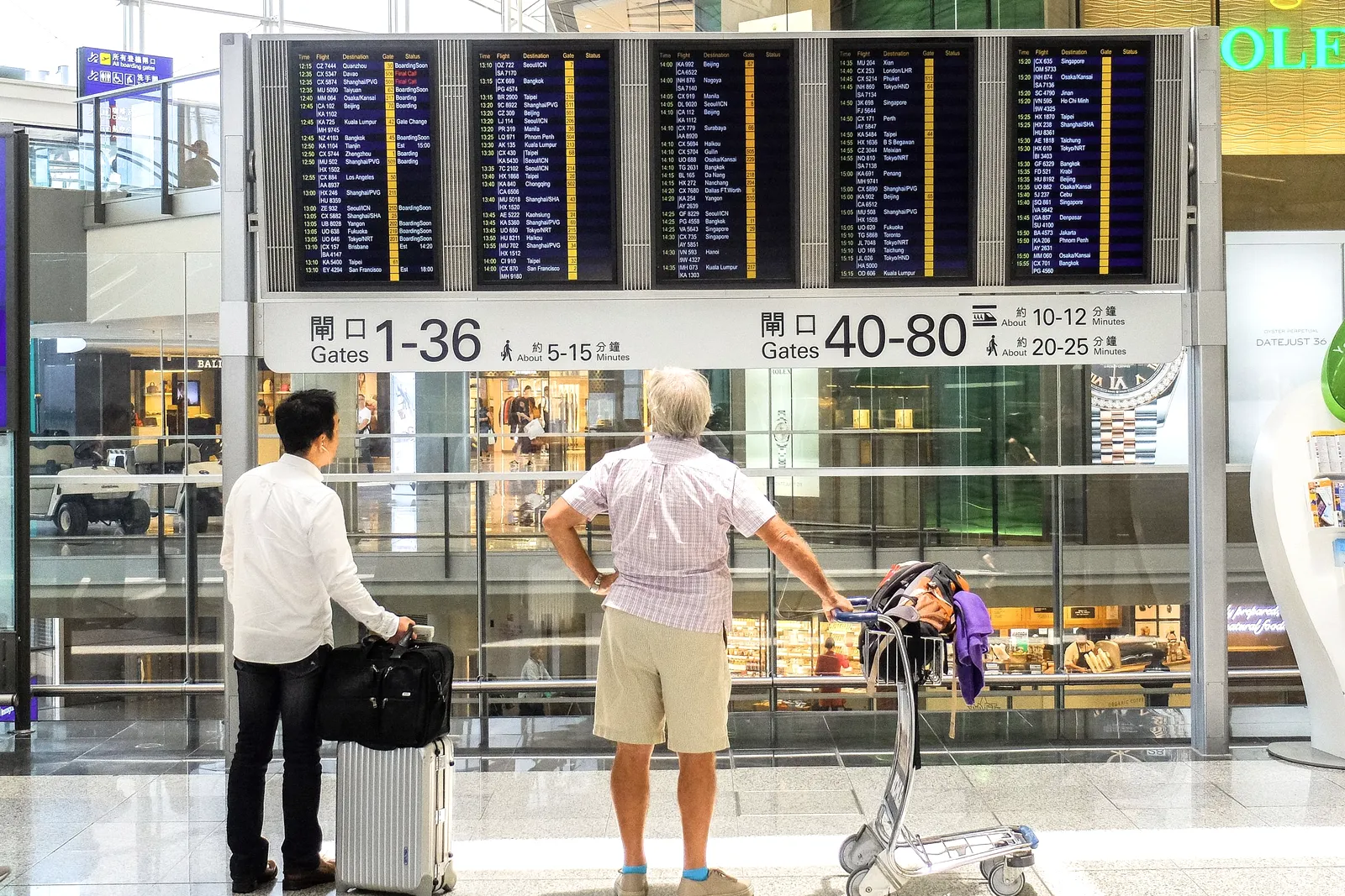 Pasajeros mirando la pantalla de vuelos en una terminal.
