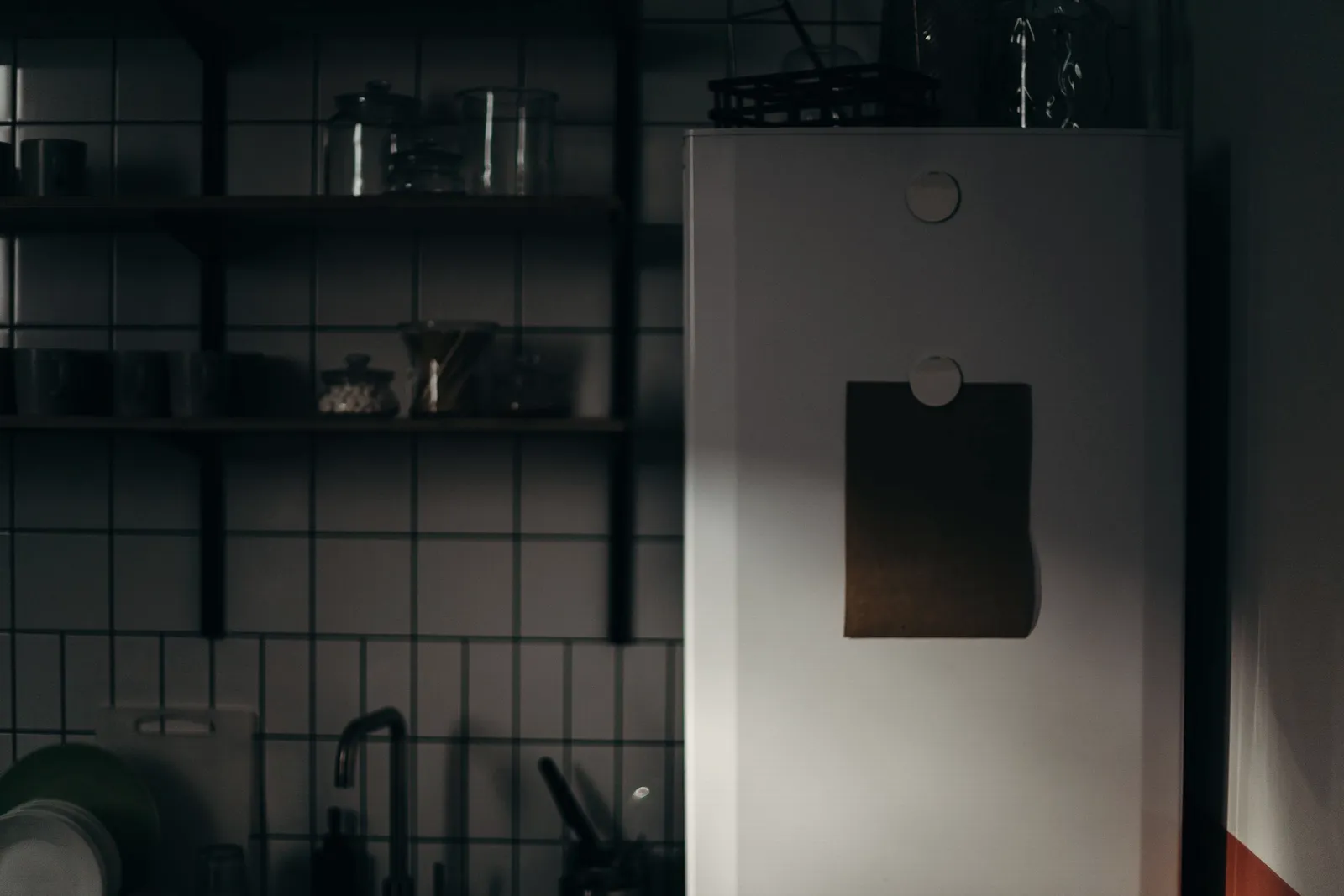 Una cocina oscura y atmosférica con el refrigerador proyectando sombras.