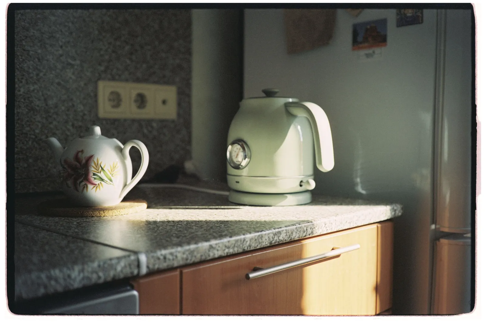 Mesada de cocina iluminada por el sol con una tetera y una pava, sin nada mas.